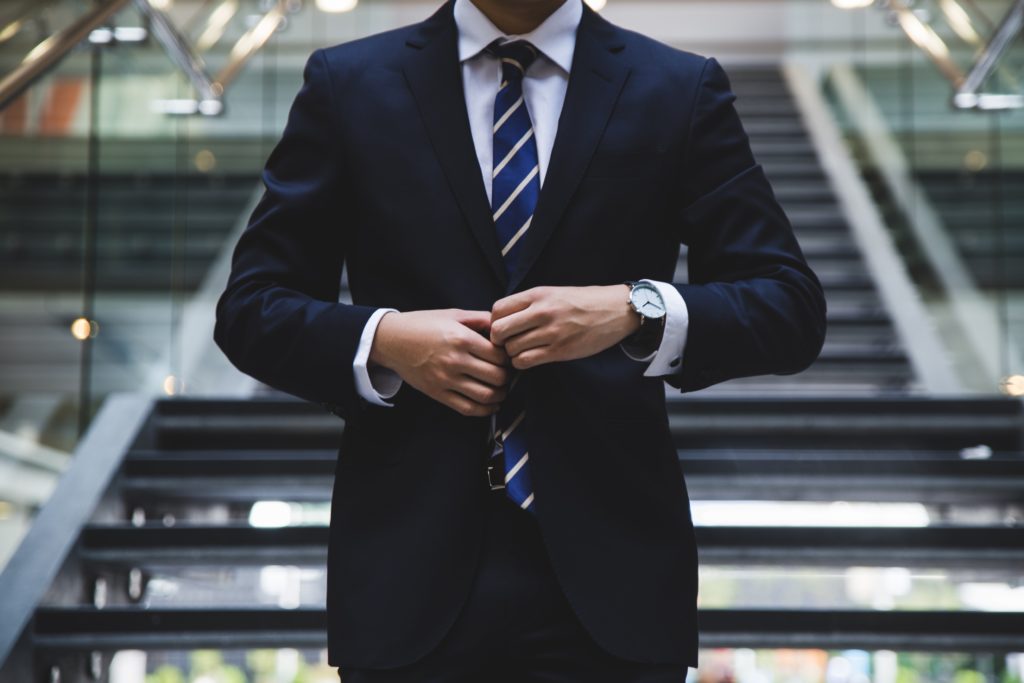 Man doing up his suit jacket.