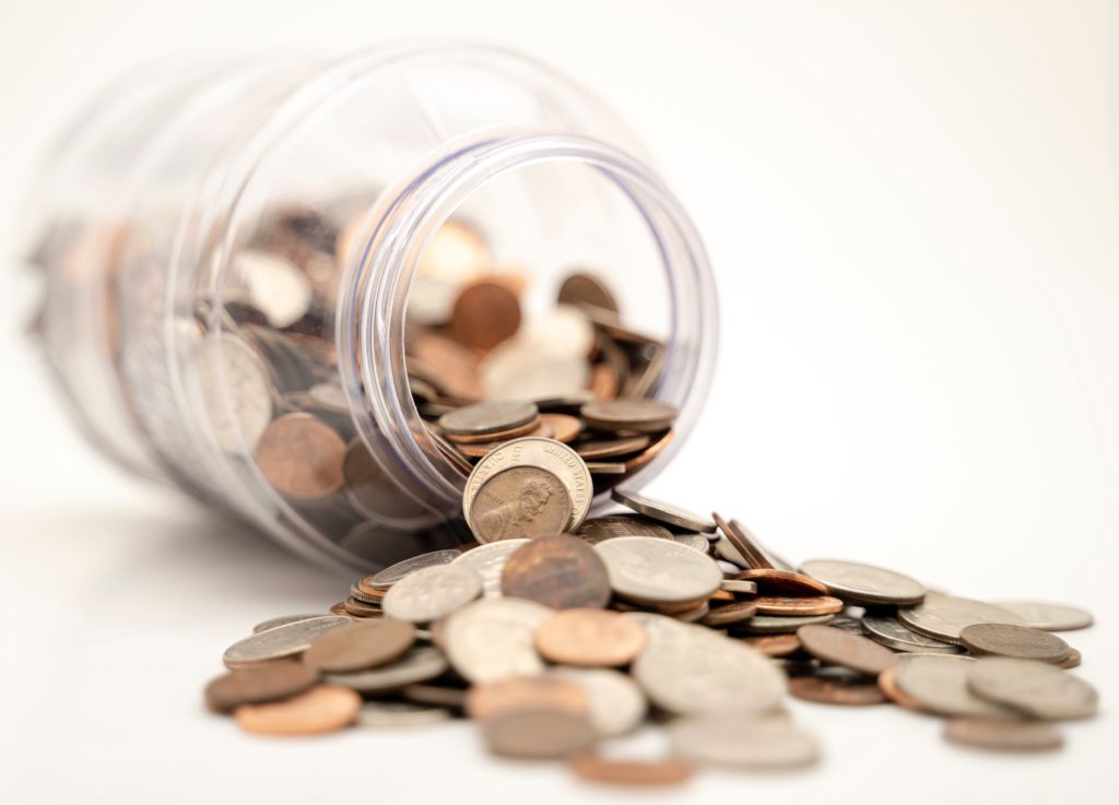 Coins falling out of a glass jar.